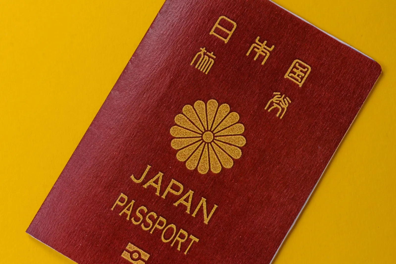 黄色の背景に置かれた、赤い表紙の日本のパスポート